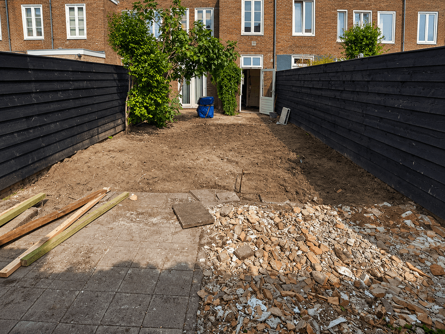 Courtyard before the renovation, with bare soil, rubble and broken-up paving.