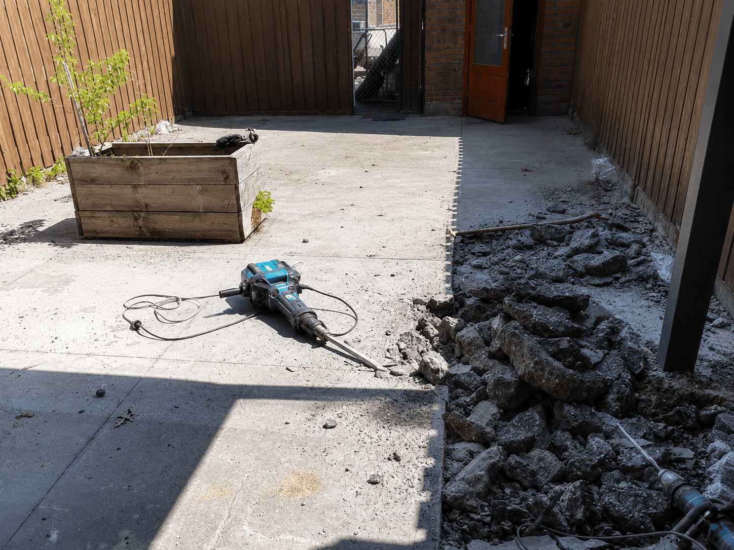 Breaking out the old concrete base in the backyard during the strip-out phase.