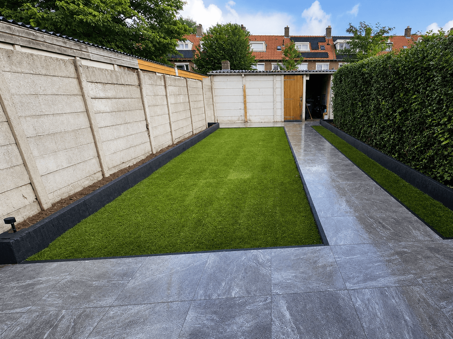 Vernieuwde stadstuin in Nederland met marmerlook keramische tegels en een strak kunstgrasgazon.