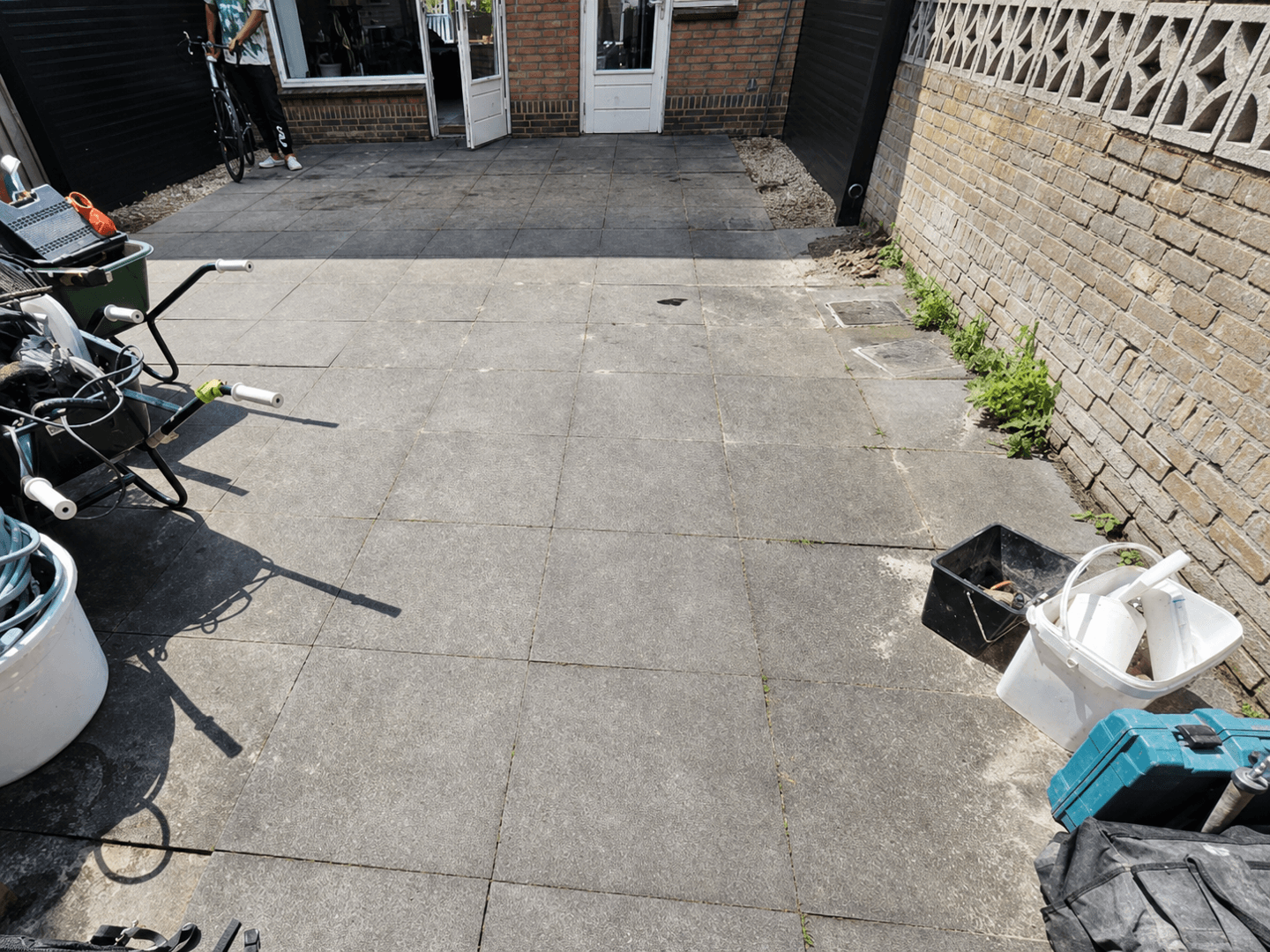 Backyard before the rebuild, with dated concrete slabs and stored belongings.