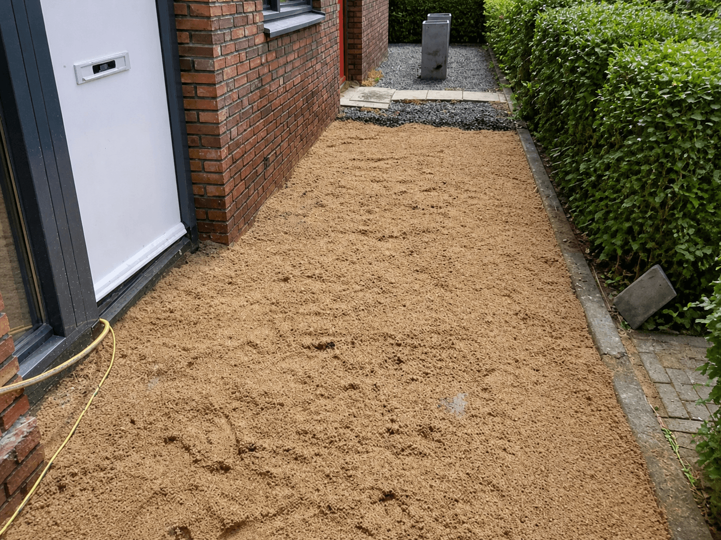 Side path along the house levelled with paving sand, ready for the new tiles.